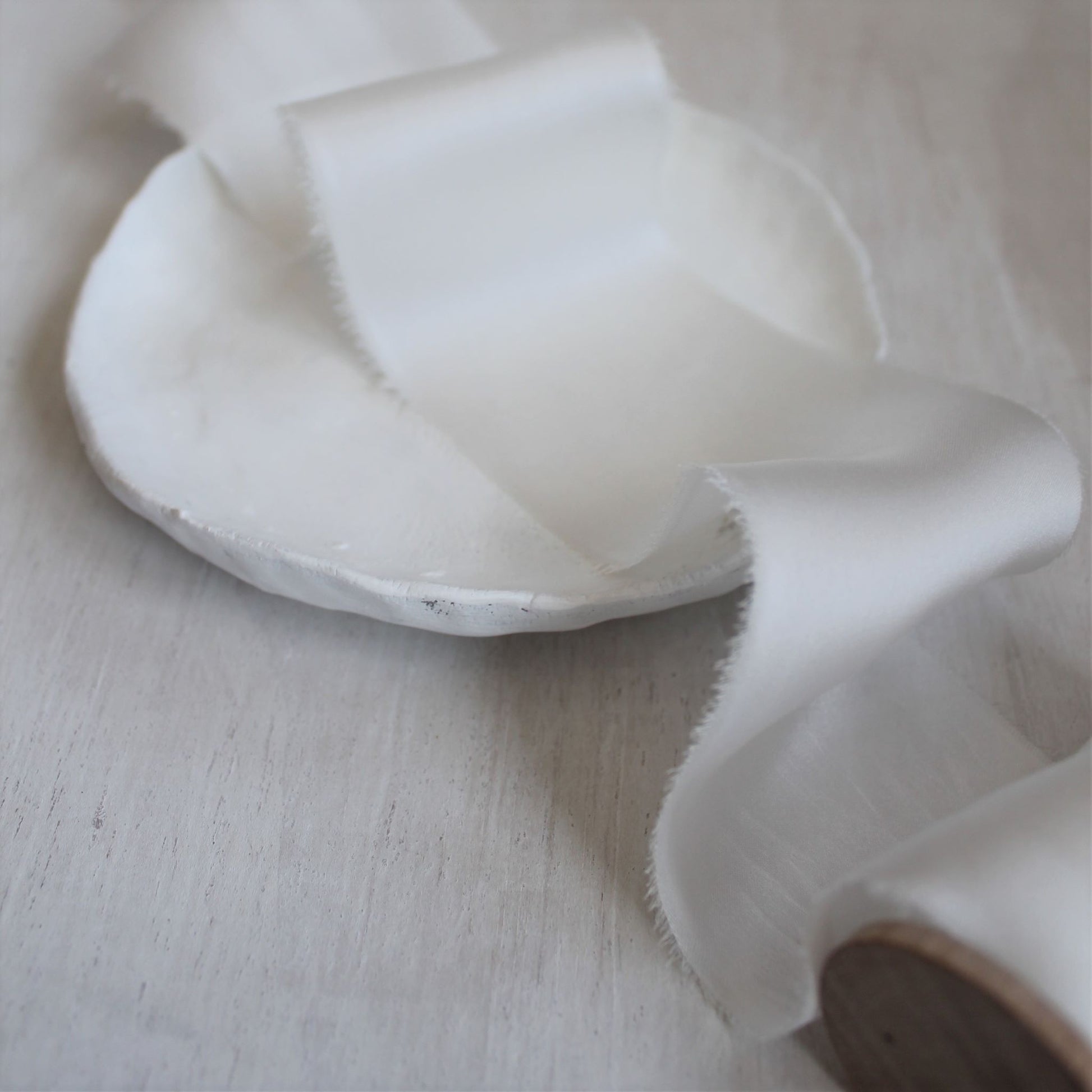 white silk ribbon with torn edges displayed in a soft, airy light, perfect for wedding styling