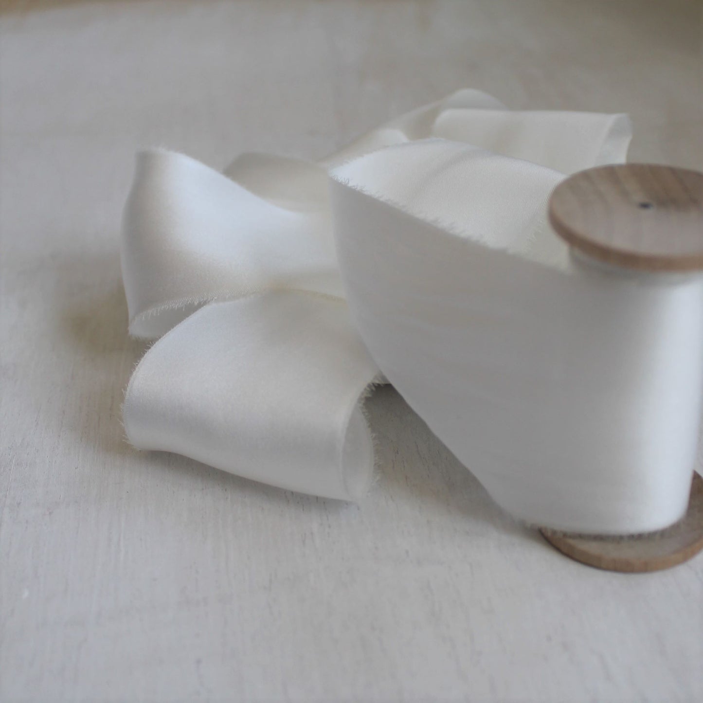 Pure white charmeuse silk ribbon displayed with other neutral tones for wedding moodboard inspiration
